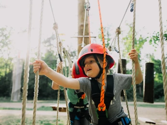 Frankfurt Climbing Forest Child wearing helmet climbing between ropes in a forest park
