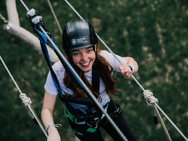 Frankfurt Climbing Forest Young woman smiling while secured on high ropes course