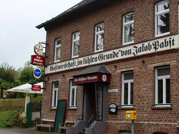 Kühle Grund in Haan Backsteingasthof "Im Kühlen Grunde" in Haan mit Außengastronomie und historischen Schildern.