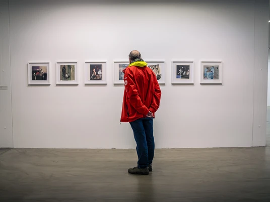Ausstellung im Museum Ratingen Besucher in roter Jacke betrachtet Kunstwerke an einer weißen Wand im Museum Ratingen.