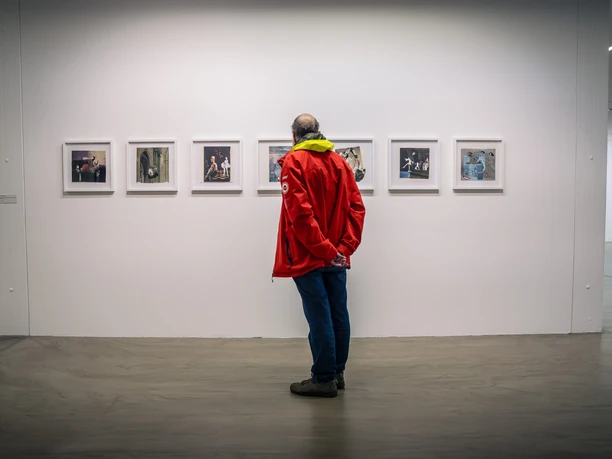 Ausstellung im Museum Ratingen Besucher in roter Jacke betrachtet Kunstwerke an einer weißen Wand im Museum Ratingen.
