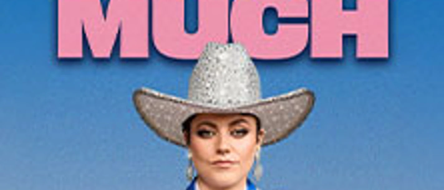 Person in glitzerndem Cowboy-Outfit vor Poster mit Schriftzug 'TAHNEE EIN TOUCH TOO MUCH'