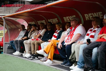 Stadionführung Besucher sitzen auf der Trainerbank im Stadion während einer Führung.