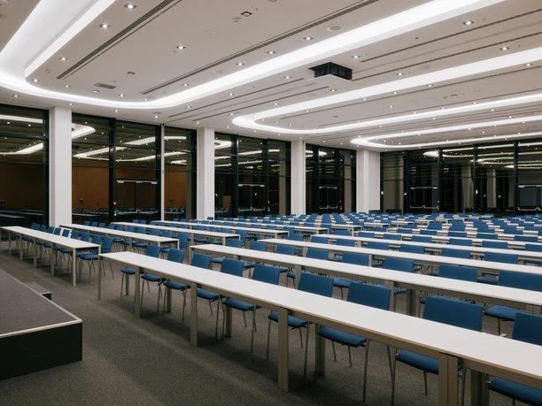 Lufthansa Seeheim - moderner Kongresssaal Ein riesiger, moderner Kongresssaal mit geschwungenen Lichtleisten und langen, weißen Tischen.