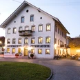 Gasthof zur Post Außen Großes Haus mit vielen Fenstern und warmem Licht am Abend.