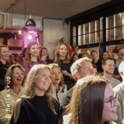 Lachendes Publikum in einem Veranstaltungsraum bei einer Comedy-Darbietung