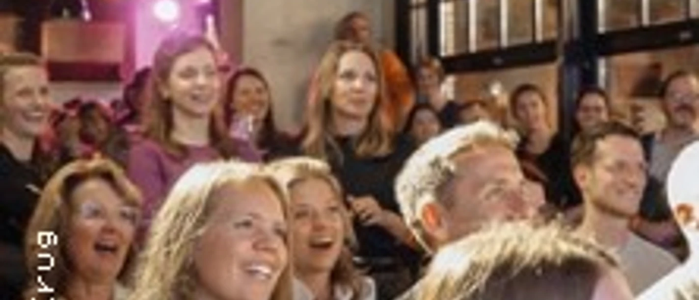 Lachendes Publikum in einem Veranstaltungsraum bei einer Comedy-Darbietung