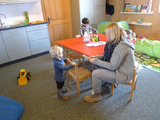 Betreuung im Kinderhort Betreuungsperson hilft Kleinkind im Kinderhort Fiescheralp beim Spielen in geschützter Umgebung
