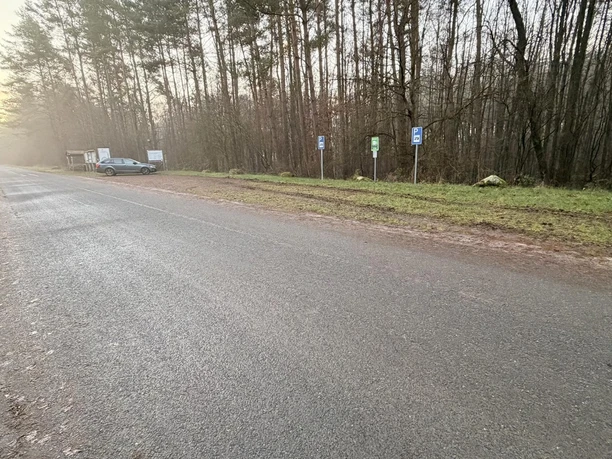 Stellplatz Wohnmobil Schwindequelle (5).JPG Asphaltierte Straße am Wald. Rechts am Grünstreifen markieren Schilder den Wohnmobilstellplatz.