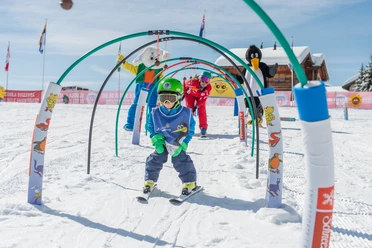 Spielerischer Parcours im Schnee Kind fährt durch Parcours im Snowgarden Riederalp mit Bögen und Spielfiguren