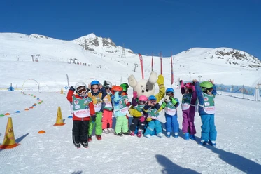 Fun together in the Snowgarden Children stand happily in the Snowgarden Fiescheralp with mascots against a snowy mountain backdrop
