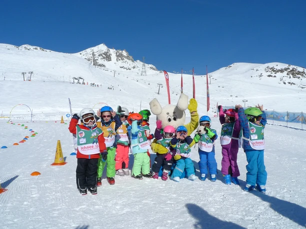 Fun together in the Snowgarden Children stand happily in the Snowgarden Fiescheralp with mascots against a snowy mountain backdrop