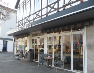 Café Feldhaus Außenansicht des Cafés mit großen Fenstern, Vordach und zwei kleinen Sitzplätzen.
