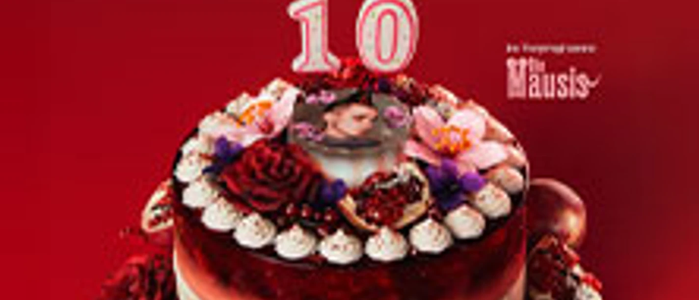 Torte mit Kerze 10, roten Blumen und Porträtdeko vor rotem Hintergrund