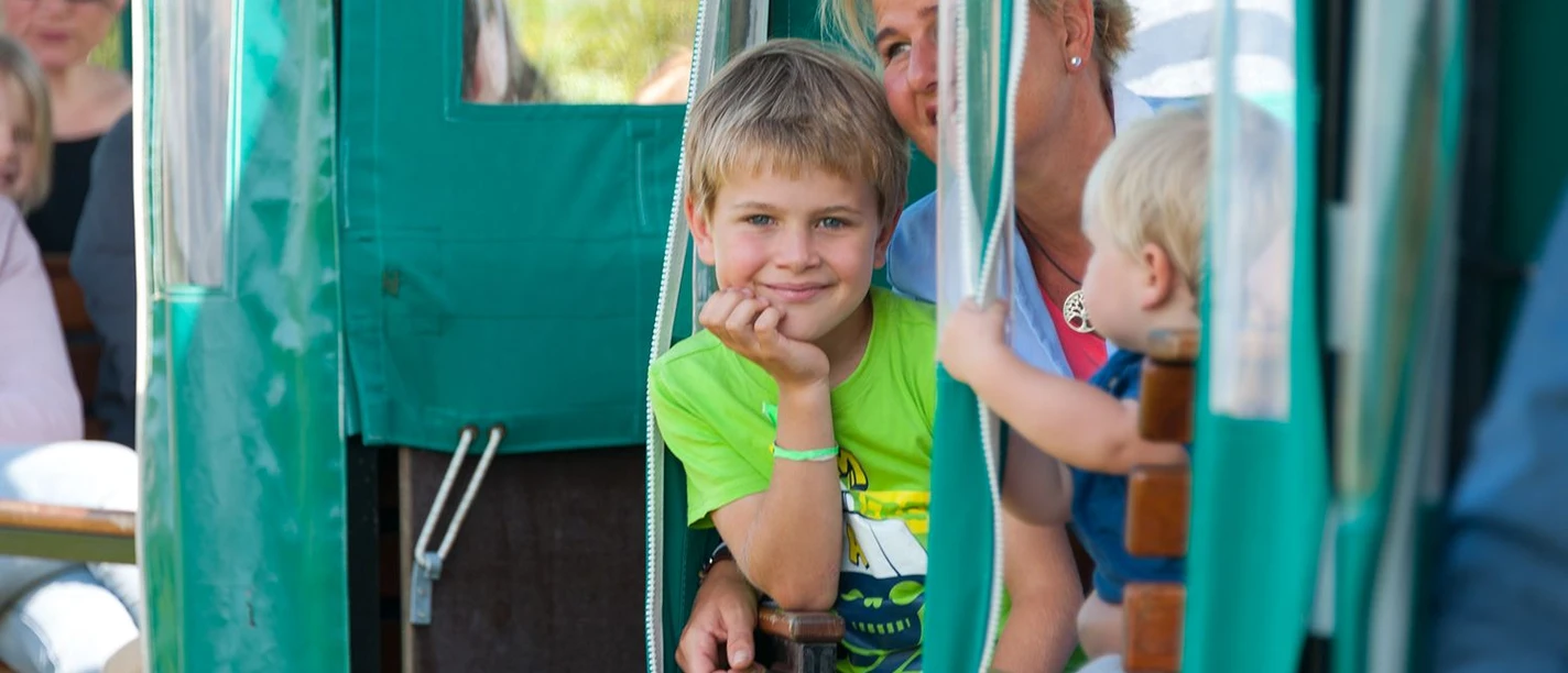 Moorbahn Ahlenmmor Frau mit zwei Kindern lächelt während einer Moorbahnfahrt durch das Ahlenmoor bei Wanna.