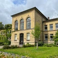 Große_Schule.jpg Historisches Schulgebäude aus gelbem Klinker mit großen Rundbogenfenstern und begrünter Fassade.