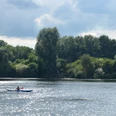 Kanufahren_Salzgittersee_HD_16zu9.JPG Eine Person im blauen Kanu paddelt auf dem glitzernden Salzgittersee vor dicht bewaldetem Ufer.