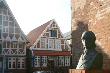 IMG_5492.JPG Eine Bronzefigur steht vor alten Fachwerkhäusern in Otterndorf.