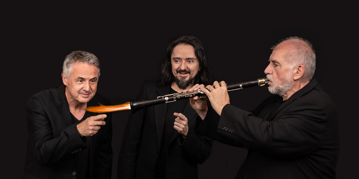 Helmut Eizel Trio Drei Männer in Schwarz, einer spielt Klarinette, orange Flamme am Schallstück als Effekt.