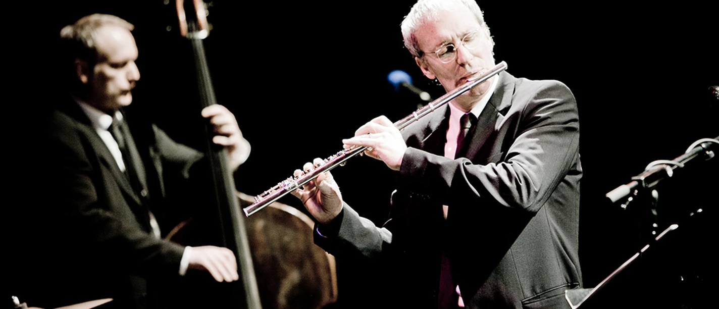 August Zirner Zwei Musiker spielen Querflöte und Kontrabass auf einer Bühne in dunkler Umgebung