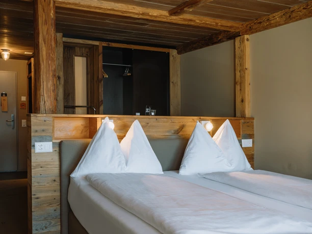 Hotelzimmer im Alpenblick Weggis mit Doppelbett und rustikalem Altholz-Interieur.