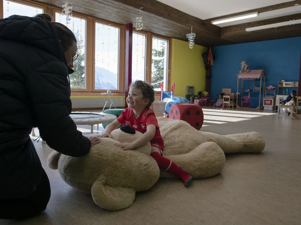 La sécurité à la garderie La personne qui s'occupe de l'enfant joue avec lui à la garderie de Bettmeralp dans une atmosphère chaleureuse et de confiance.