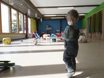 Entdecken und Bewegen Kleinkind bewegt sich selbstständig im Kinderhort Bettmeralp durch den hellen SpielraumToddler moves independently through the bright playroom in the Bettmeralp day nurseryUn petit enfant se déplace de manière autonome dans la salle de jeux lumineuse de la crèche Bettmeralp.
