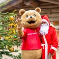 2025_12_16_PM_Weihnachten.jpg Weihnachtsmann und Maskottchen Willi Wildpark winken neben geschmücktem Baum im Wildpark.