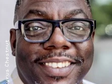 Porträt eines lächelnden Mannes mit Brille vor unscharfem Hintergrund