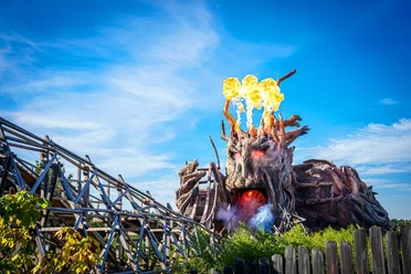 heide-park-resort-soltau-biest-colossos.jpg Feuerspeiendes Colossos-Holzachterbahn-Monster im Heide Park Soltau Resort unter blauem Himmel.