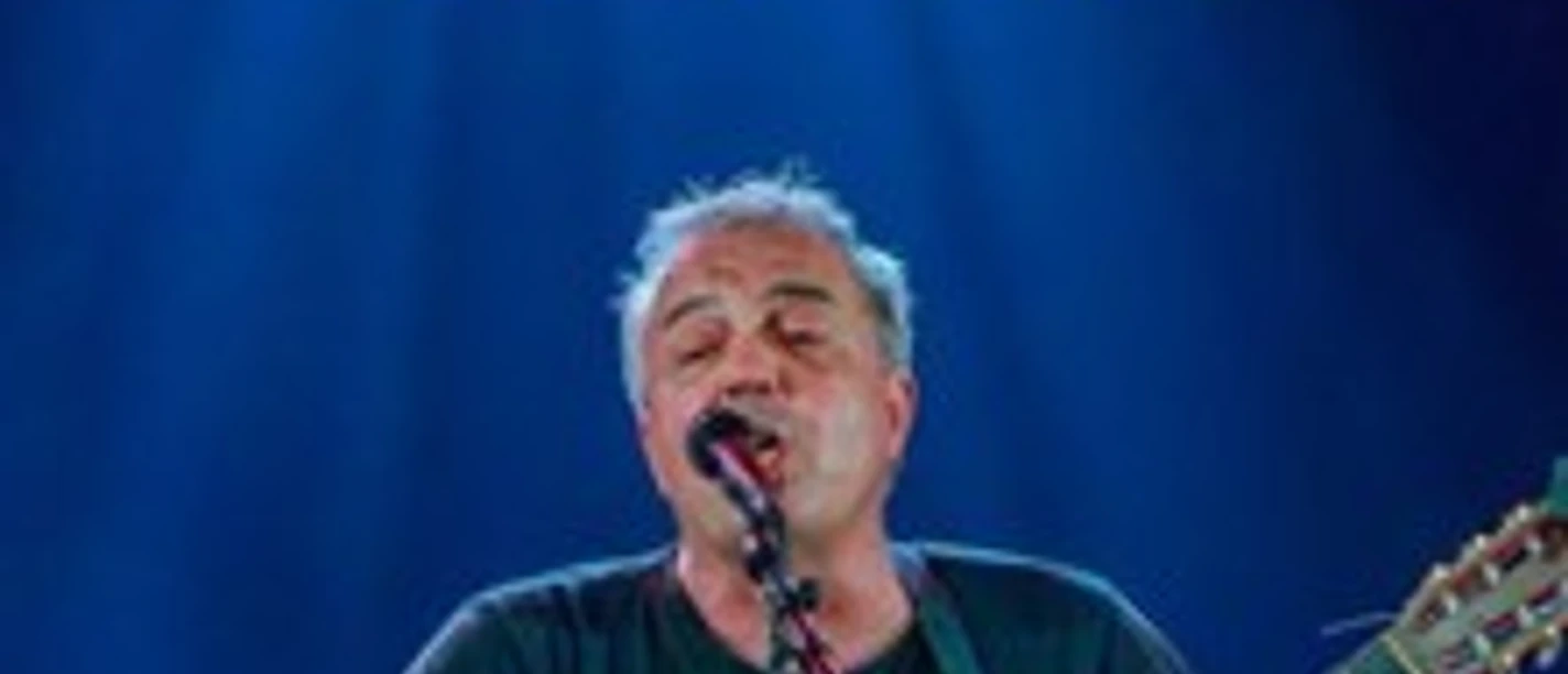 Sänger mit Gitarre auf einer beleuchteten Bühne, während über ihm der Schriftzug Party Time steht