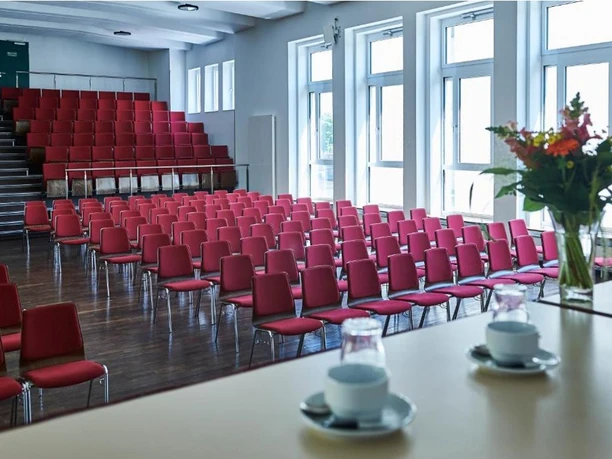 Haus der Jugend e.V. - Großer Saal Großer Saal in Reihenbestuhlung und bodentiefen Fenstern.