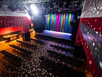 Bahnhof Langendreer Bochum Nachweis Christoph Partsch_4.jpg Bühnenraum mit buntem Vorhang, Stuhlreihen und Lichtpunkten einer Disco-Kugel