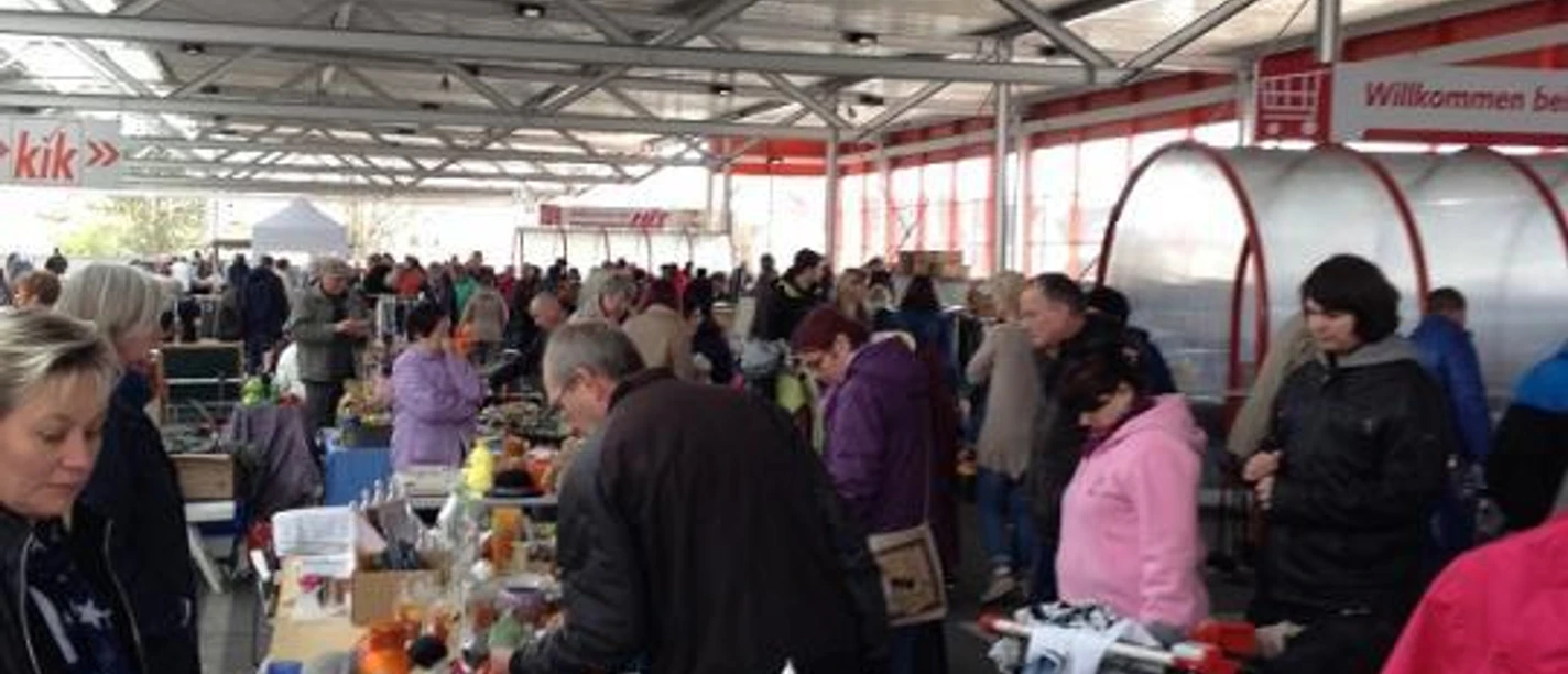 Besucher stöbern an dicht gefüllten Flohmarktständen auf dem überdachten Parkdeck.