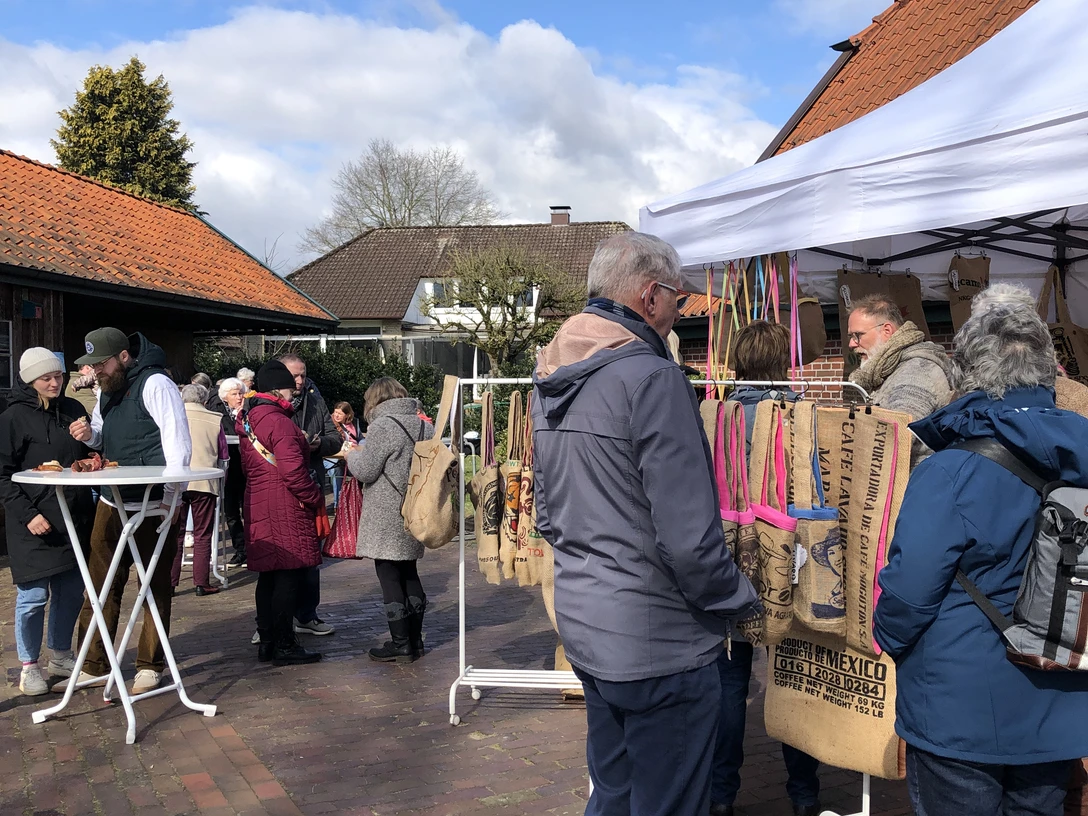 Kreativmarkt März 2025 (16).JPG Besucher stöbern an Ständen mit handgefertigten Taschen auf einem sonnigen Hofmarkt im März.