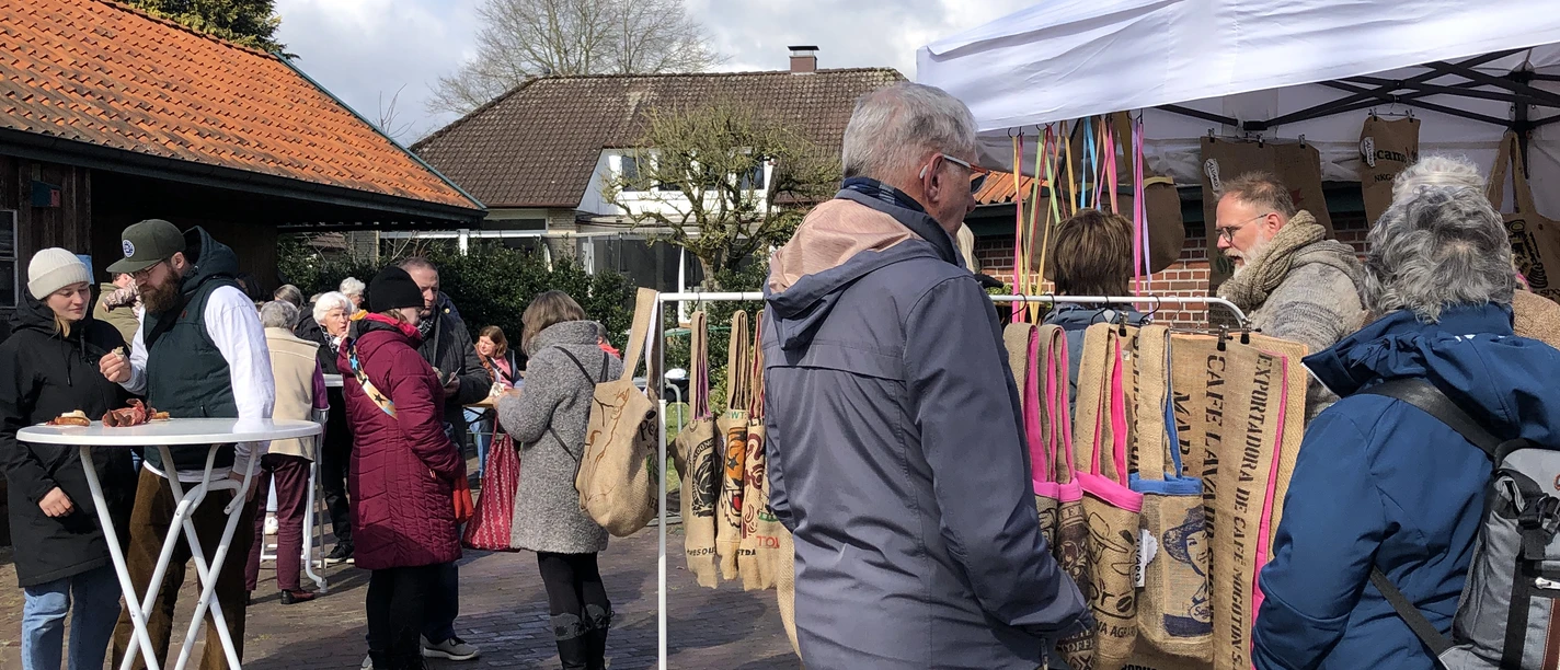 Kreativmarkt März 2025 (16).JPG Besucher stöbern an Ständen mit handgefertigten Taschen auf einem sonnigen Hofmarkt im März.