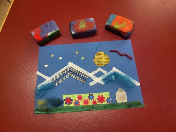 Kreatives Basteln im Kinderhort Bettmeralp Kinderhort Bettmeralp zeigt ein kreatives Bastelprojekt mit Stoff, Filz und Farben auf einem roten Tisch