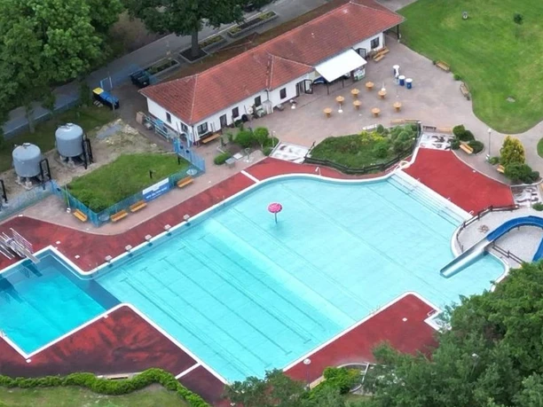 Vue aérienne de la piscine en plein air de Böhlitz avec la piscine, les pelouses, les arbres et les bâtiments du complexe.