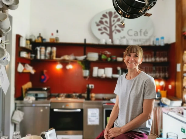 Café Schaffner Eine Person lächelt. Ein Café hat offene Regale und warmes Licht.