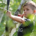 Elles Erlebnisparcours - Ausflugsziele in der Region Leipzig Ein kleiner Junge übt Bogenschießen, hält den Bogen konzentriert in den Händen und zielt aufmerksam.