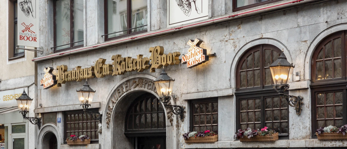 Brauhaus Em Kölsche Boor Historische Brauhausfassade mit dunklen Fenstern, Laternen und Blumenkästen am Eigelstein Köln