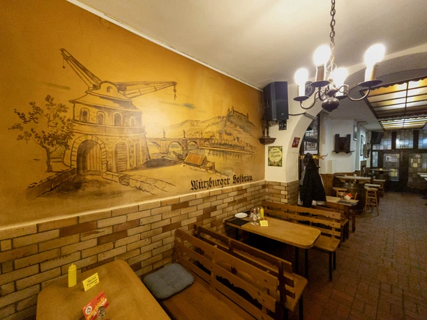 Weinhaus Vogel Rustikale Gaststube mit großem Wandgemälde, Holzbänken und warmem Licht.