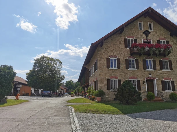 Museumcafe Großes Haus aus Stein mit Blumen und Gästen im Hof bei Sonne.