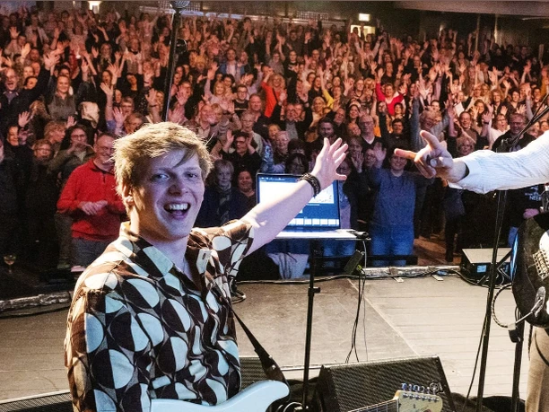 RUDELSINGEN.png Gitarrist und Pianist auf der Bühne mit jubelnden Besuchern im Hintergrund