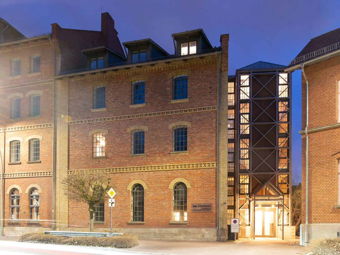 WF-Bundesakademie-Gästehaus.jpg Backsteingebäude mit vielen Fenstern. Heller Eingang mit Glasfront bei Abendlicht