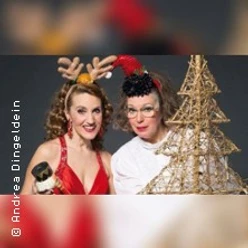Zwei Personen in weihnachtlichen Kostümen posieren neben einem dekorativen Baumgestell.