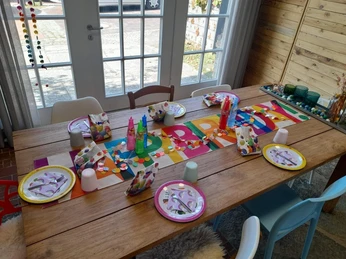 Querfeldein - Kindergeburtstag Ein bunt gedeckter Tisch für einen Kindergeburtstag vor einem Panoramafenster.