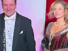 Mann im Smoking und Frau im 20er-Jahre-Kleid vor rotem Vorhang.