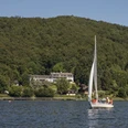Ein Segelboot auf dem Edersee und im Hintergrund Waldhotel Wiesemann