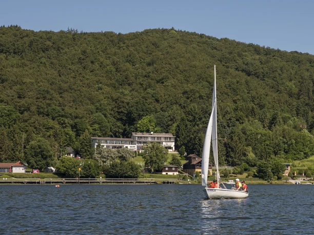 Ein Segelboot auf dem Edersee und im Hintergrund Waldhotel Wiesemann